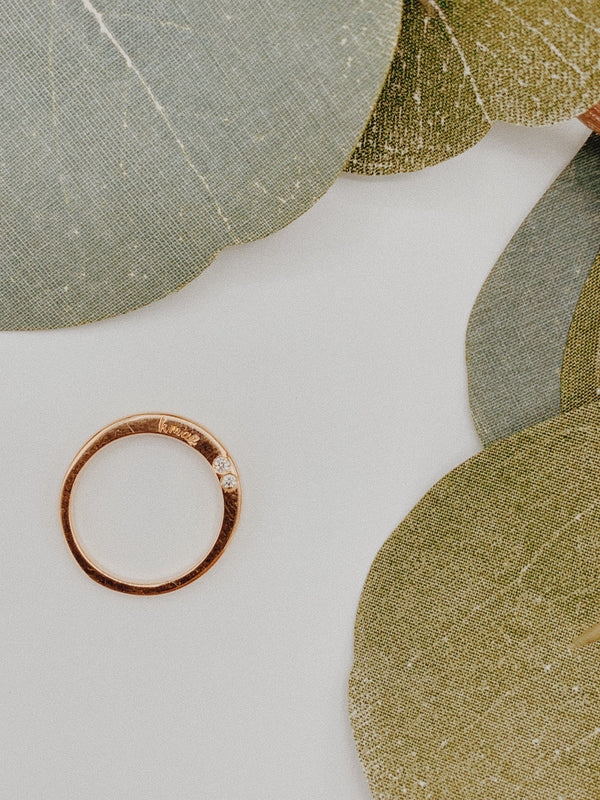 Rose gold ring with two 2mm diamonds bezeled and ‘k mae’ engraved.