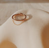  Rose gold ring with bezeled pear-shaped gem with dangled chain.