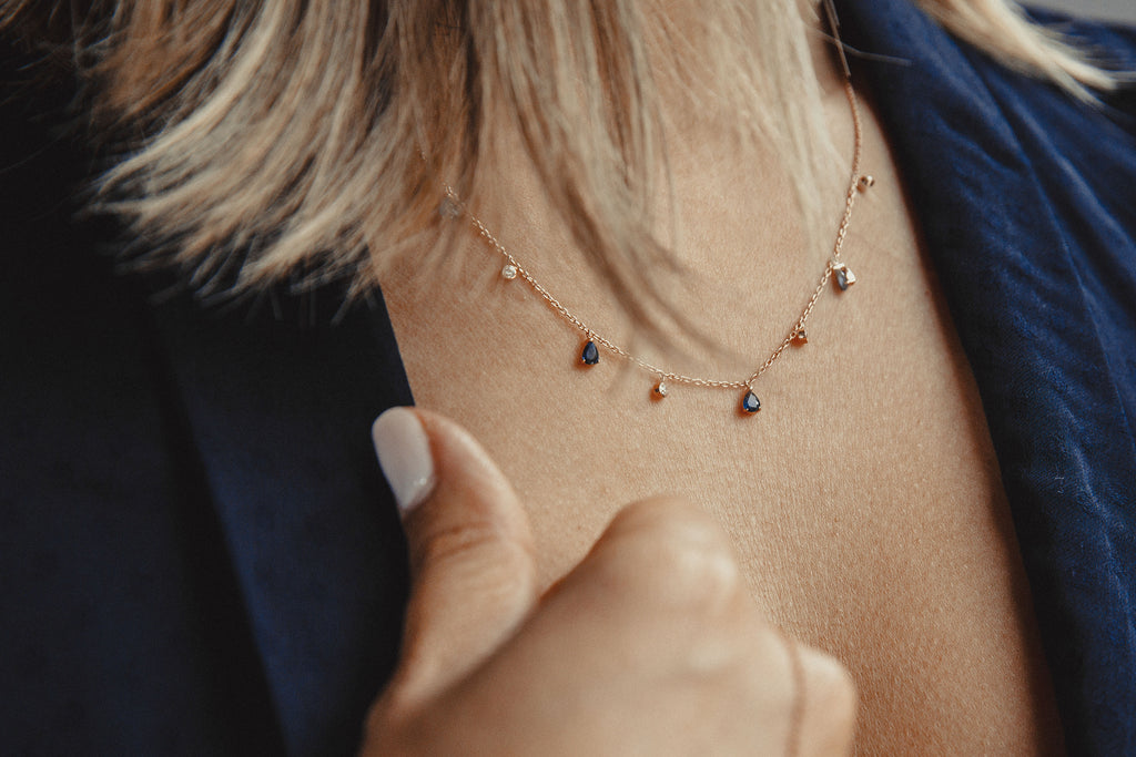 Rose gold necklace with five diamonds and four blue sapphires.